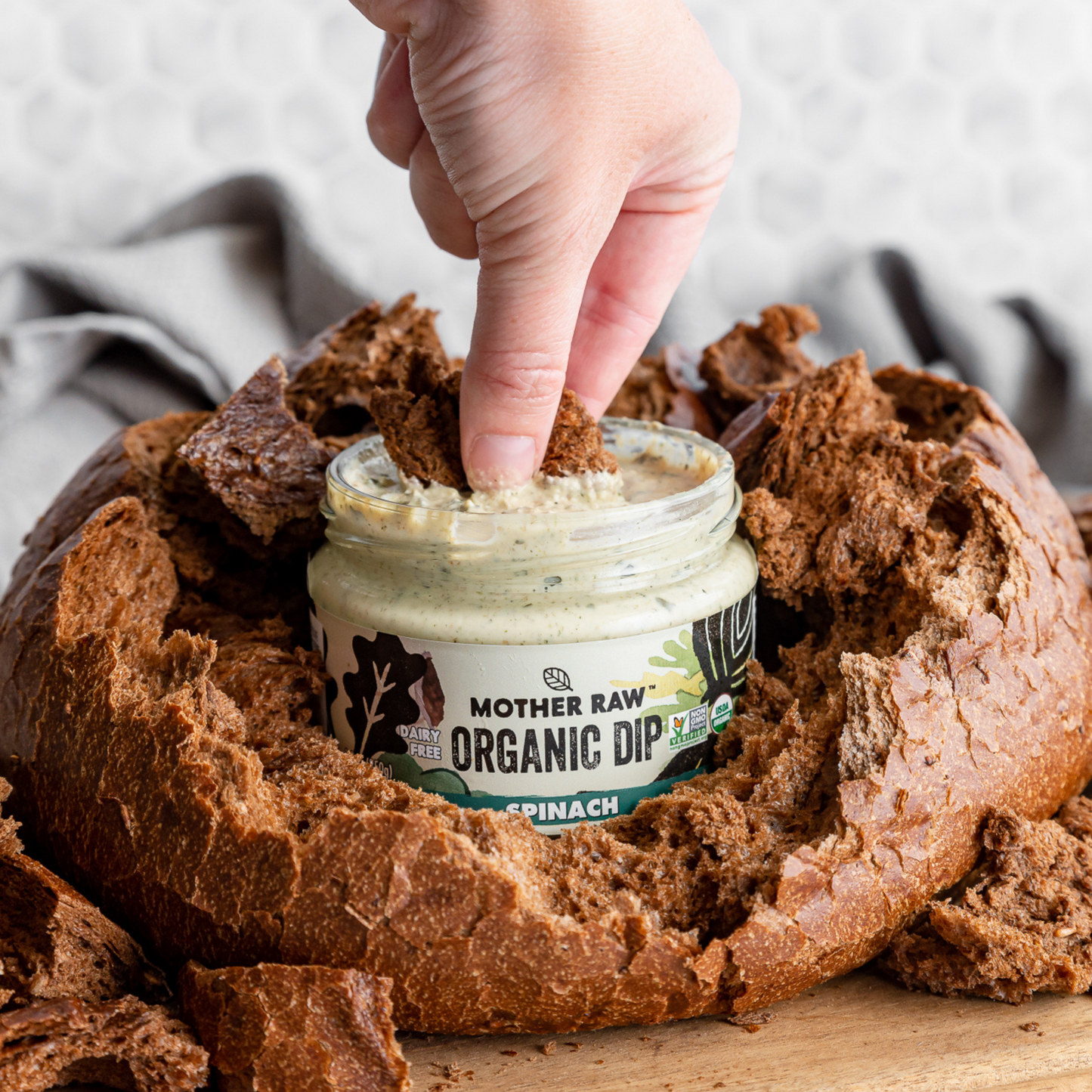 Finger with pumpernickel dipping into Mother Raw Organic Vegan Dairy Free Dip