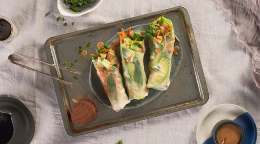 Three Asian Salad Wraps served on a small plate on top of a baking sheet, with several sauces in dishes nearby
